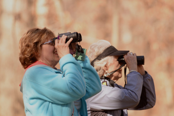 Two women looking through binoculars.