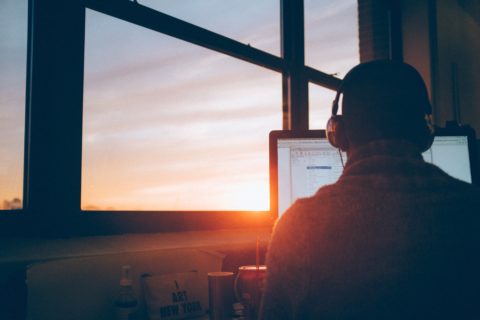 Person sitting at computer at sunrise.