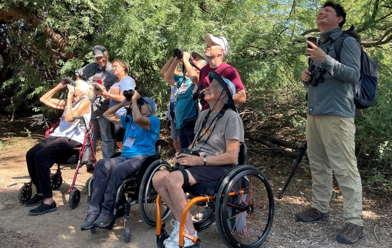 A group of people birding with different mobility challenges.