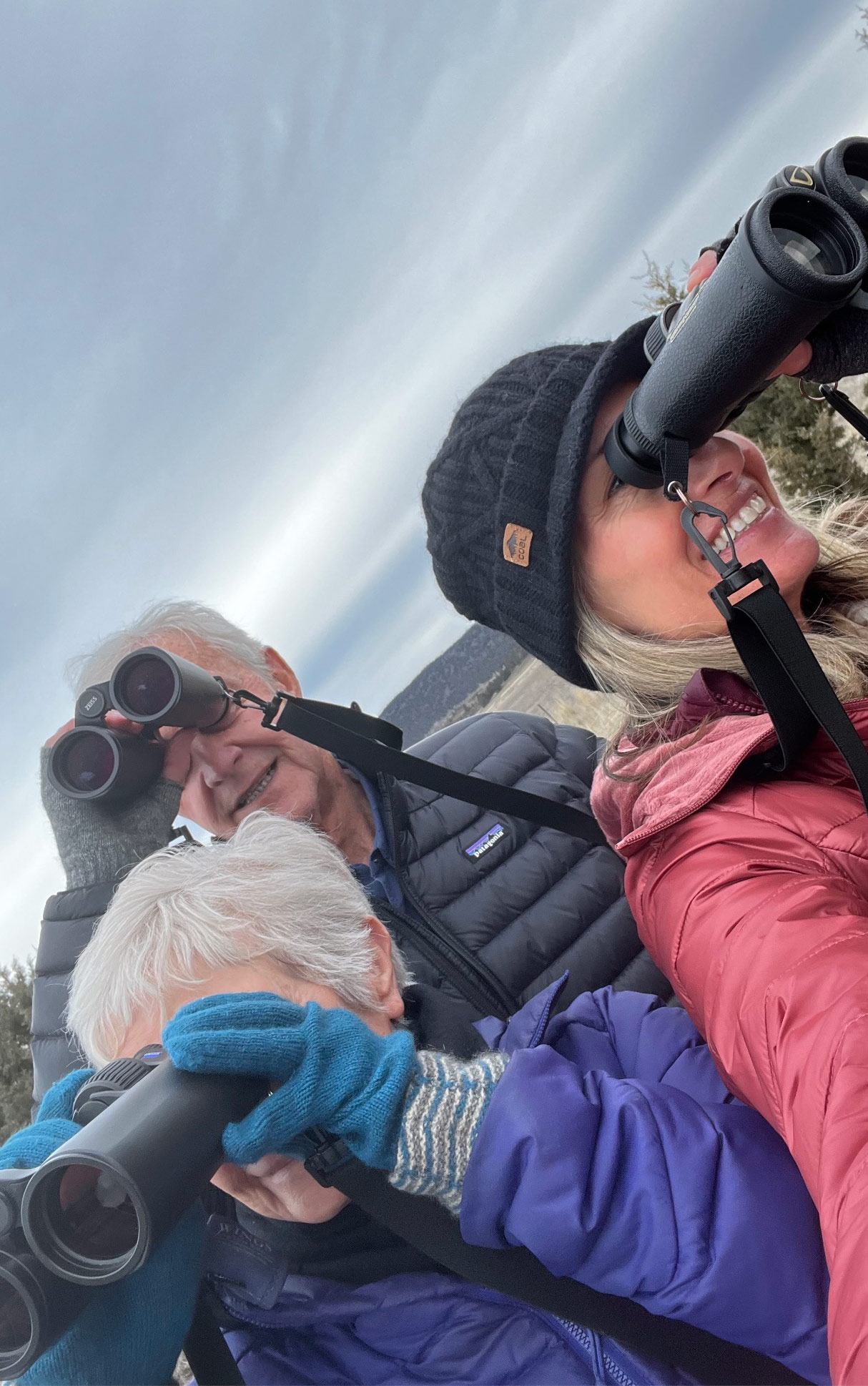 Three people look through binoculars in three different directions