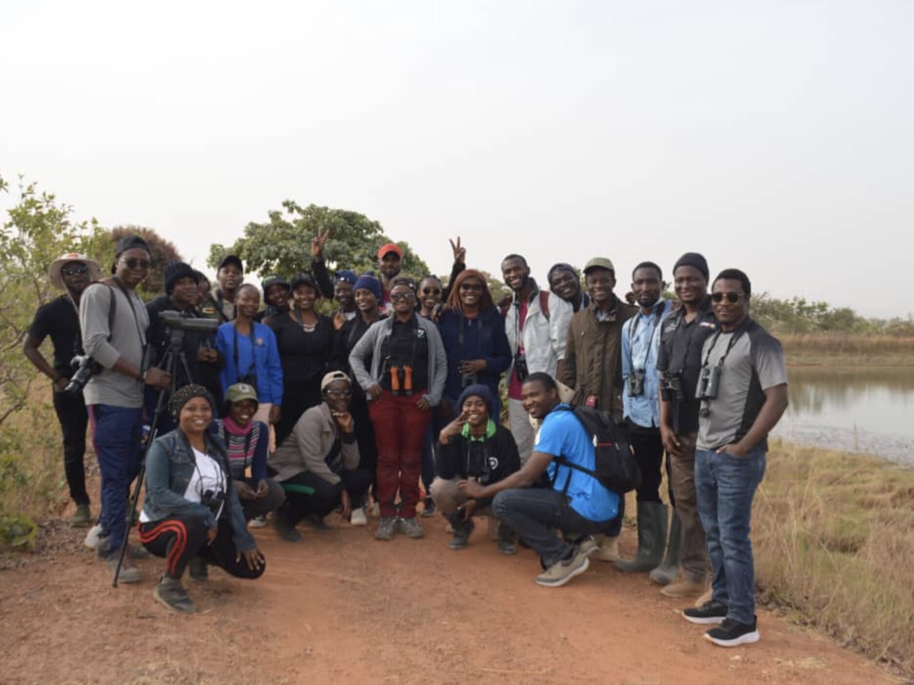 a group of birdwatchers stands on a dirt road