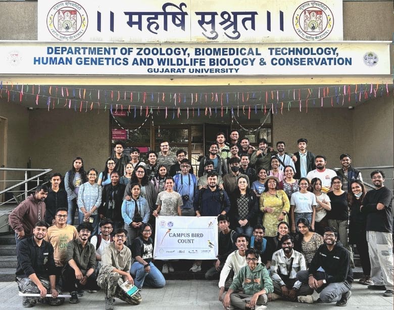 A large group of people smiling while holding a poster.