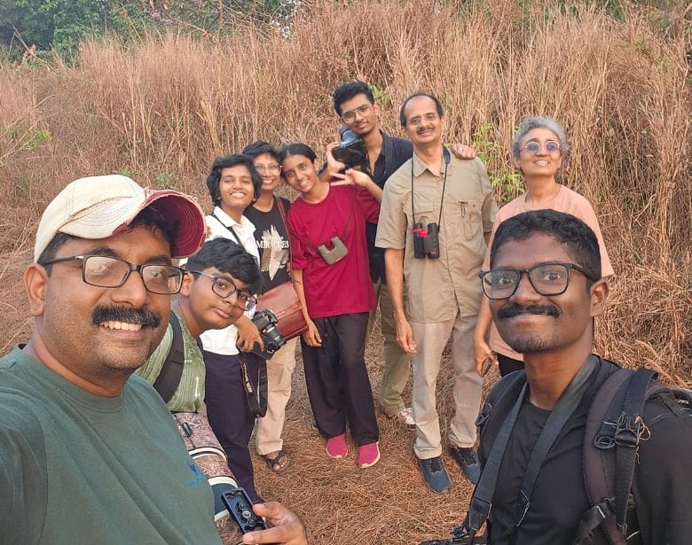 A group of people with binoculars smiling.