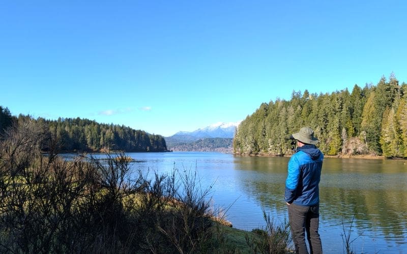 A person birdwatching in front of a large body of water.
