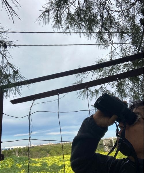 A person birdwatching with binoculars.