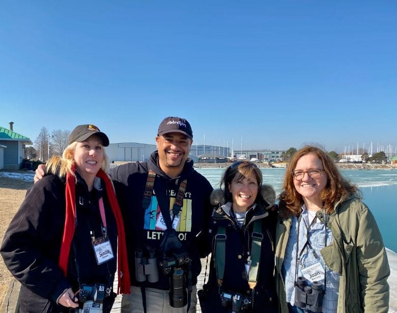 Group of people smiling with binoculars.