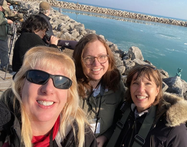 Group of people smiling in front of a body of water. 