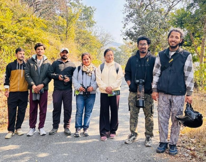 Group of smiling people with birdwatching equipment.
