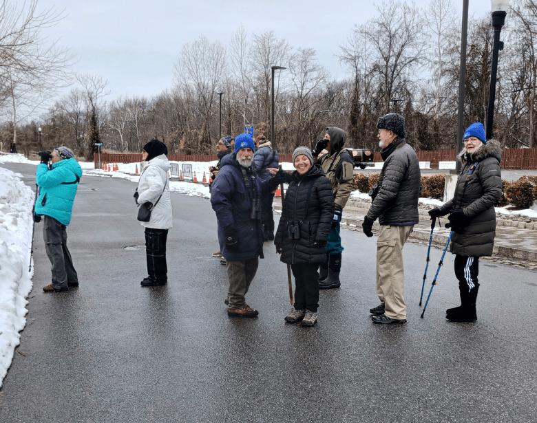 A smiling group of people with birdwatching equipment.