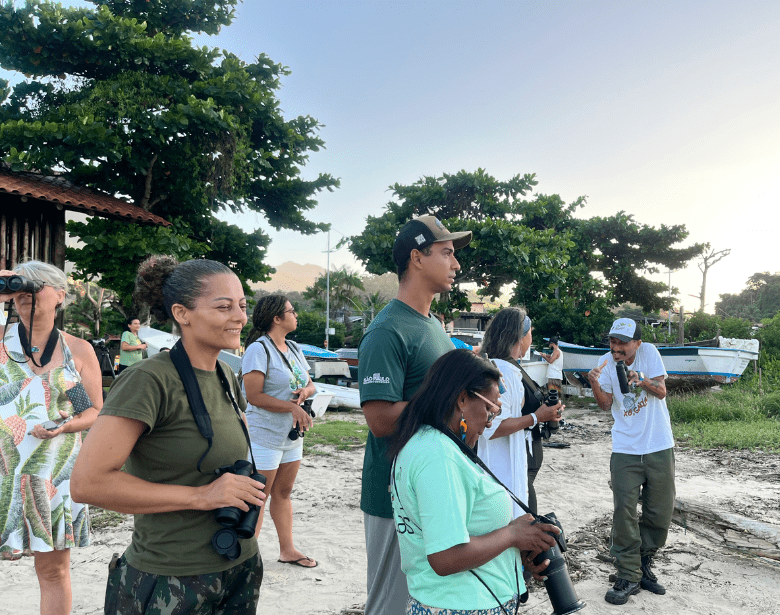 A smiling group of people birdwatching.
