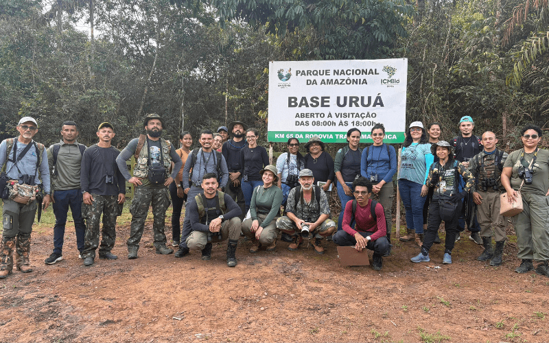 A smiling group of people with birdwatching equipment.