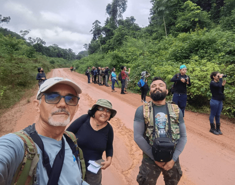 A smiling group of people birdwatching.