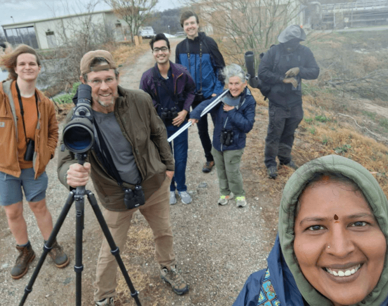 A smiling group of people birdwatching.