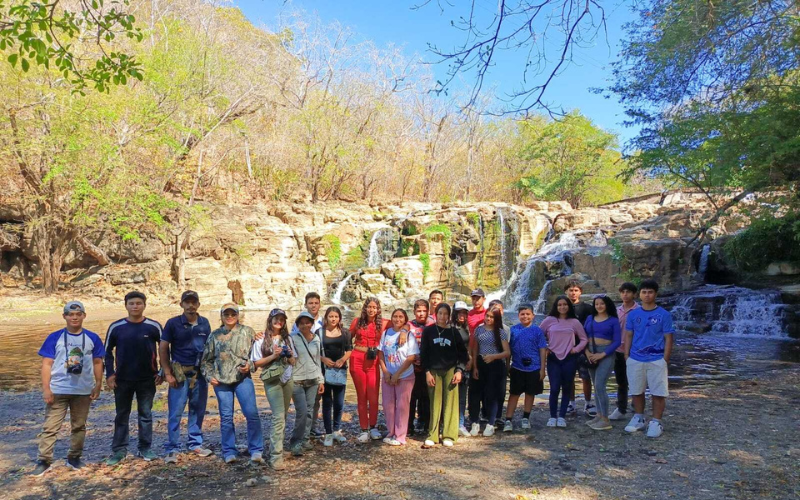 A group of smiling people standing in front of small waterfalls.
