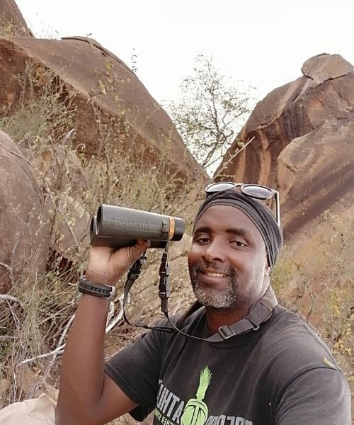 A person smiling while holding binoculars.