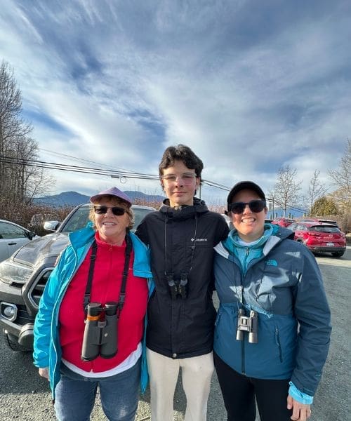Three people smiling with binoculars.