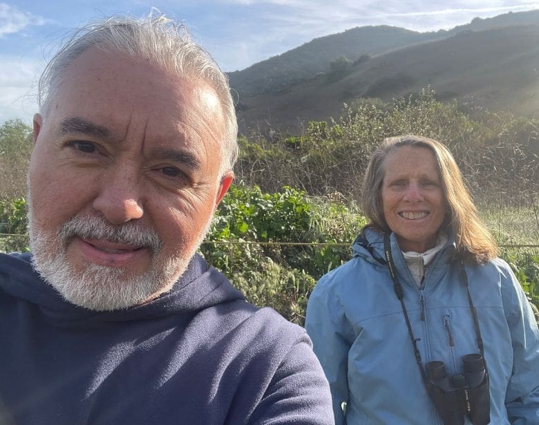 Two people smiling with binoculars.