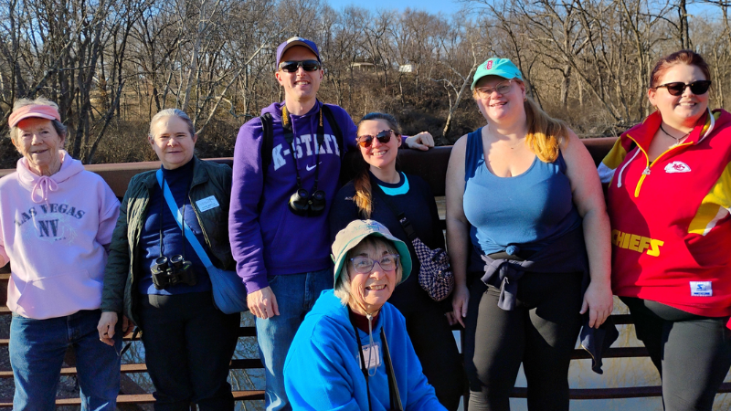 A smiling group of people with birdwatching equipment.